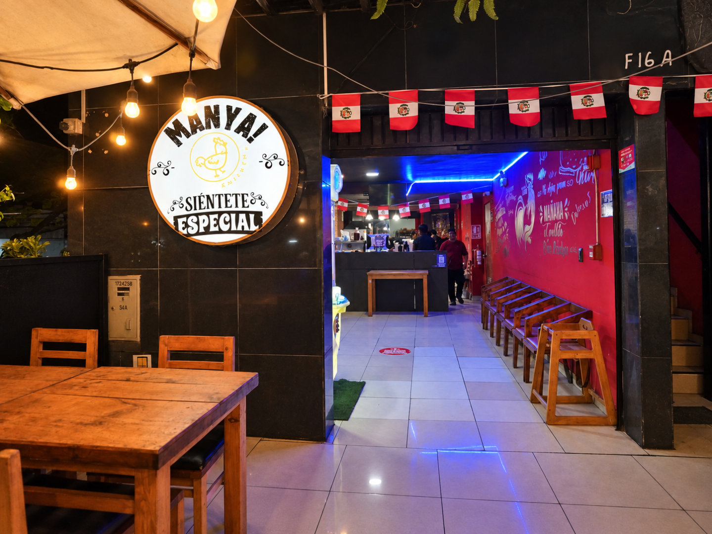 Ingreso interior de Manya Chicken Grill con el logo circular en la pared
